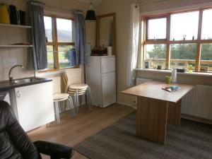a kitchen with a table and some chairs and windows at Björkin – Cozy Cabin with excellent view in Akureyri