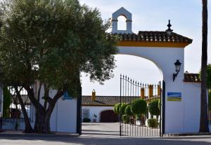 a white building with a gate and a tree at Puerta de Algadir in El Puerto de Santa María