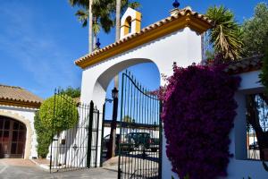 a gate with purple flowers in front of a church at Puerta de Algadir in El Puerto de Santa María