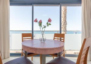 a vase with flowers on a table in front of a window at Apartamentos Varadero Sea View in Cala del Moral