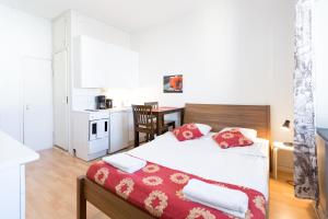 a bedroom with a bed with red pillows and a kitchen at Apartment Hotel Tampere MN in Tampere