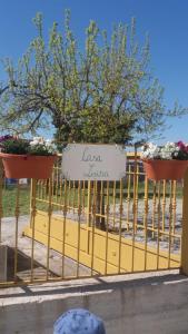 een bord op een geel hek met bloemen erop bij Casa Luisa in Palazzo