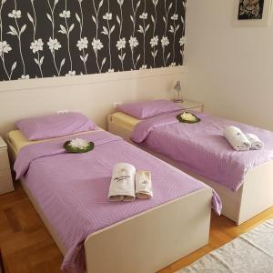 2 Betten in einem Zimmer mit lila Bettwäsche in der Unterkunft Adela Apartments Žnjan Split in Split