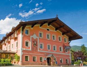 ein großes orangefarbenes Gebäude mit einem Dach in der Unterkunft Hotel Reitlwirt in Brixen im Thale