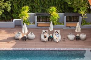 two women are sitting in pillows next to a pool at Phuvaree Resort in Patong Beach