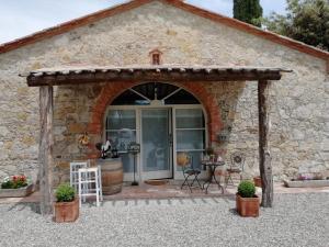 a stone building with an entrance with a table and chairs at B&B CASAGRANDE in Quercegrossa