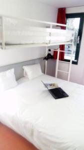 a bedroom with a bed with a laptop on it at Premiere Classe Périgueux - Boulazac in Boulazac