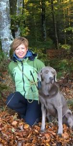 Eine Frau, die neben einem Hund im Wald kniet in der Unterkunft Chalet Grünegg in Grindelwald