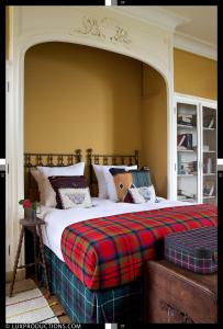 a bedroom with a large bed with a plaid blanket at Monastere de Brucourt in Brucourt