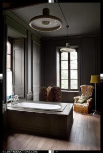 ein großes Bad mit einer Badewanne und einem Stuhl in der Unterkunft Monastere de Brucourt in Brucourt