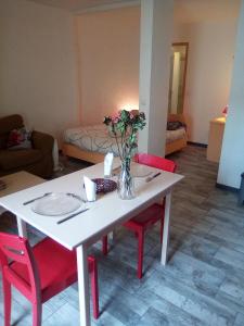 een witte tafel met rode stoelen en een vaas met bloemen bij Charmant studio centre ville Mirepoix in Mirepoix