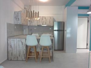 a kitchen with a counter with stools and a refrigerator at Gala Apartment in Nea Potidaea