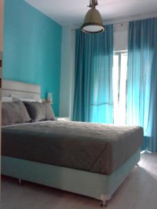 una camera da letto con un letto con pareti blu e una finestra di Gala Apartment a Nea Potidaea