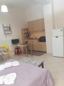 a kitchen with a table and a white refrigerator at Cozy apartment in the center of Aighion Achaia - ground floor - ισόγειο στουντιο in Aigio