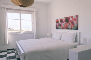 a white bedroom with a bed and a window at Blue Kaouki in Sidi Kaouki