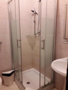 una ducha con una puerta de cristal junto a un lavabo en Botel Inn en Roma