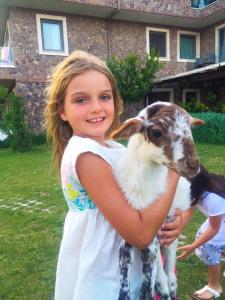 a little girl holding a baby goat in a yard at Assos Alis Farm Boutique Hotel & Spa in Behramkale