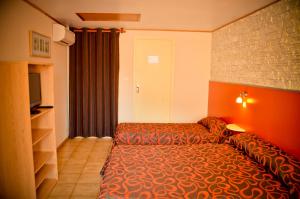 a hotel room with a bed and a television at Hotel Les Pins in Hourtin