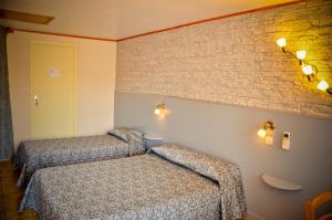 a room with two beds and a brick wall at Hotel Les Pins in Hourtin