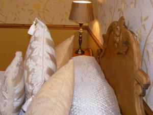 um quarto com uma cama com almofadas e um candeeiro em The Dog and Partridge em Langsett
