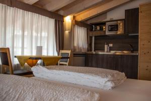 a bedroom with a bed and a table and a kitchen at DolceVita Ambiez B&B in San Lorenzo in Banale