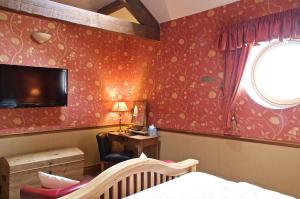 um quarto com papel de parede vermelho, uma cama e uma secretária em The Dog and Partridge em Langsett
