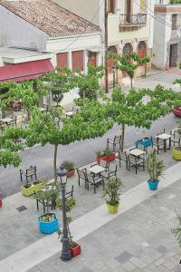 een groep tafels en banken met bomen op een binnenplaats bij Alexis's House in Pylos