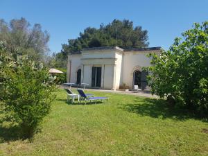 un edificio blanco con sillas en el césped en Il giardino del Salento - Lecce - Casa Vacanze, en Cavallino di Lecce