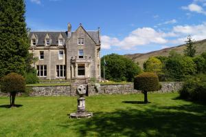 a large house with a statue in the yard at Glengarry Castle Hotel in Invergarry