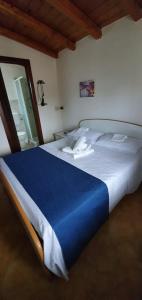 a large white bed with a blue blanket on it at Beb Eclissi in Fontane Bianche
