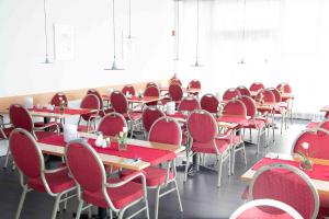 una stanza piena di tavoli e sedie rosse di Hotel am Südtor a Backnang