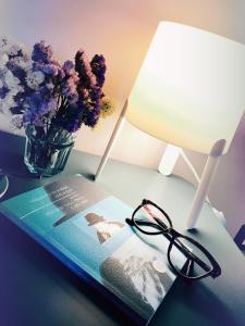 een tafel met een boek en een lamp en bloemen bij Sweet Holiday Home in Bernalda