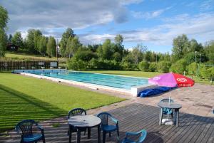 a pool with tables and chairs and an umbrella at Åsens Vandrarhem Uvboet in Älvdalen