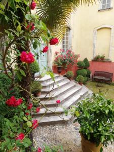 a garden with red flowers and plants and a building at Demeure de Digoine "Chambre d'Hotes" in Bourg-Saint-Andéol