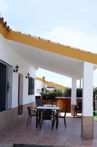 a patio with a table and chairs under a roof at TRUJILLO HOLIDAY HOME con PISCINA in Conil de la Frontera