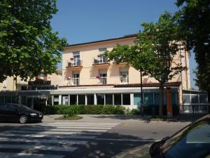 a large building with cars parked in a parking lot at HOTEL OTELLO in Punta Marina