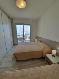 リニャーノ・サッビアドーロにあるResidence La Dunaのベッドルーム1室(ベッド1台、大きな窓付)