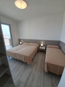 リニャーノ・サッビアドーロにあるResidence La Dunaのベッドルーム1室(ベッド2台、大きな窓付)