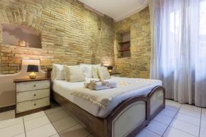 1 dormitorio con 1 cama grande y pared de ladrillo en Arcobaleno Rooms en Cagliari