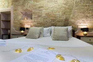 a bed with white pillows and pillows on it at Arcobaleno Rooms in Cagliari