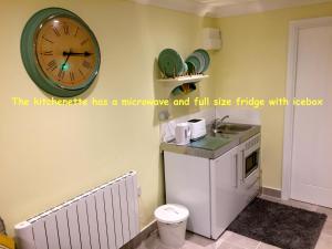 a clock on the wall of a kitchen with a sink at The Sunroom Studio in Wimborne Minster