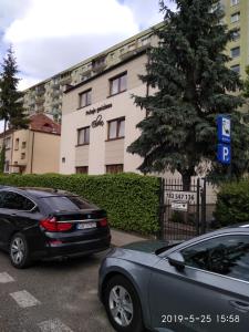 2 voitures garées sur un parking en face d'un immeuble dans l'établissement Eleven Pokoje, à Gdynia