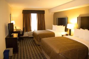 a hotel room with two beds and a television at Sigma Inn & Suites in Melville