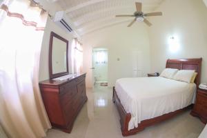 a bedroom with a bed and a dresser and a mirror at Hibiscus Villa @ DraxHall in Mammee Bay