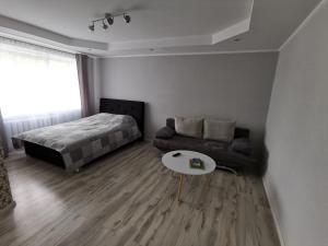 a bedroom with a bed and a couch and a table at Central Sun in Daugavpils
