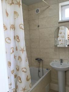 a bathroom with a sink and a shower curtain with shells at Адмирал 3. Вилла in Koblevo