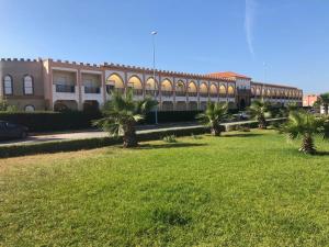 ein Gebäude mit Palmen auf einem Grasfeld in der Unterkunft Duplex in El Jadida