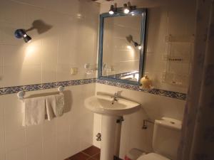 a bathroom with a sink and a toilet and a mirror at Casa Tia Emilia in Villar de Plasencia