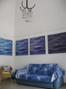 a blue couch in a room with four paintings at Il mare in un Boccaccio in Polignano a Mare