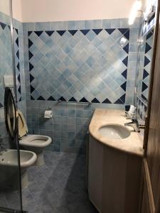 bagno piastrellato blu con lavandino e servizi igienici di Residence Cala Moresca a Golfo Aranci